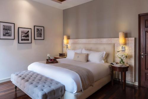a bedroom with a large white bed and a bench at Hacienda Peña Pobre in Mexico City