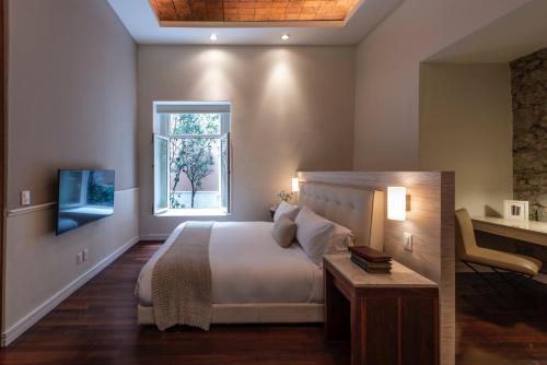 a bedroom with a bed and a window and a television at Hacienda Peña Pobre in Mexico City
