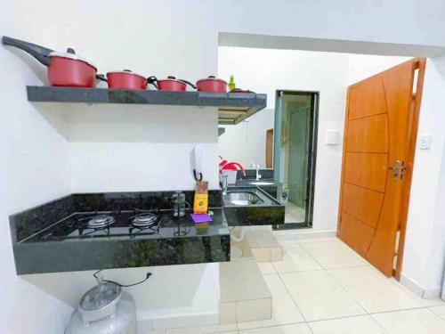 a kitchen with a stove and a sink with pots and pans at Suíte aconchegante no Centro de Caratinga - kitnet in Caratinga