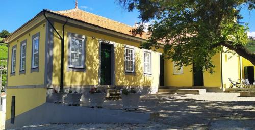 a yellow house with white windows and a tree at Casa de São Roque - Lamego in Cambres