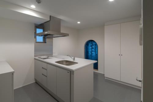 a white kitchen with a sink and a window at Seven Stories in Nagoya