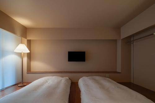 a bedroom with two white beds and a lamp at Seven Stories in Nagoya