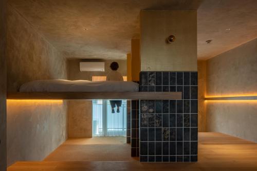 a room with a bed and a person standing in a bedroom at Seven Stories in Nagoya