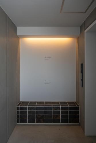 a hallway with a wall with a light on it at Seven Stories in Nagoya