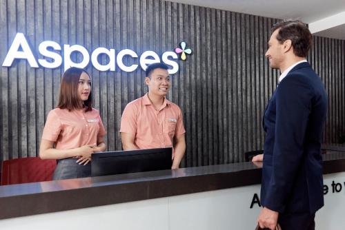 two men and a woman standing in front of a computer at Aspaces Serviced Apartments - Vinhomes West Point in Hanoi