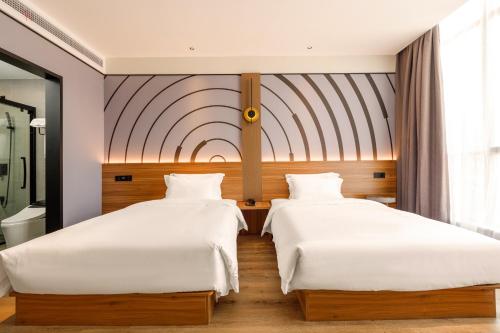2 łóżka w pokoju hotelowym z białą pościelą w obiekcie zmaxhotels 无锡新加坡工业园机场店 w mieście Wuxi