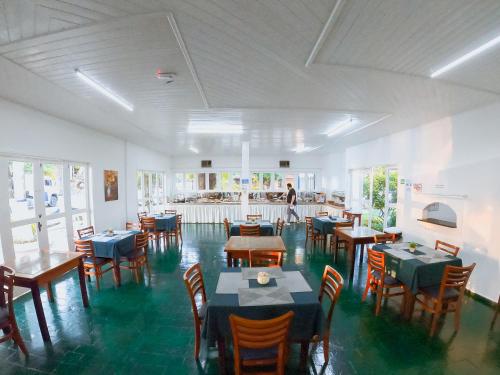 a restaurant with tables and chairs and a person in the background at Hotel Arrastão in São Sebastião