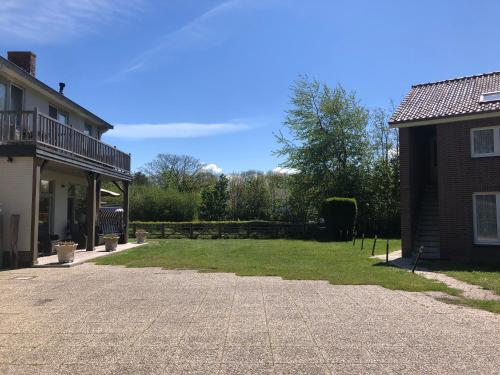 
a house with a large yard and a large building behind it at Hotel Panta Rhei Cadzand-Bad in Cadzand
