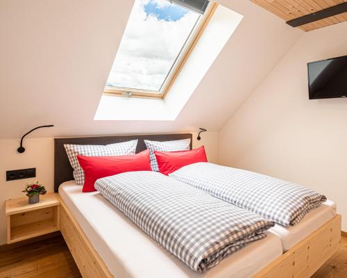 a bedroom with a bed with red pillows and a window at Nattrars Huimat in Obermaiselstein