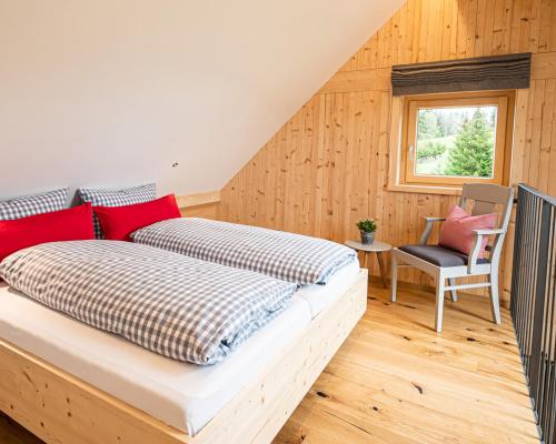 a bedroom with a bed and a chair and a window at Nattrars Huimat in Obermaiselstein