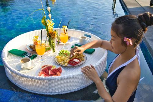 珀尼達島的住宿－NG Sweet Home，坐在餐桌上吃一盘食物的女人