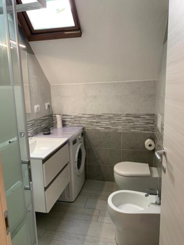 a bathroom with a toilet sink and a washing machine at Accogliente casetta a Calaverde, Pula. in Pula