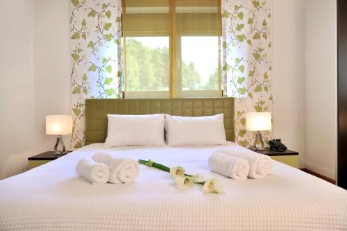 a bedroom with a bed with towels and flowers on it at Sani Polyastron Hotel & Spa in Sani Beach