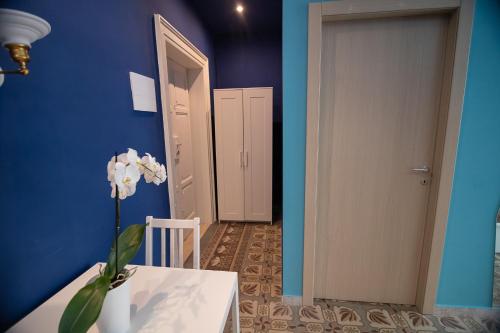 a blue room with a table and a vase with white flowers at DEAS B&B in Trani
