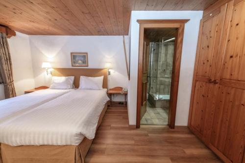 a bedroom with a bed and a walk in shower at Hotel Steinbock in Klosters