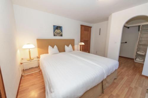 a bedroom with a large white bed and two lamps at Hotel Steinbock in Klosters