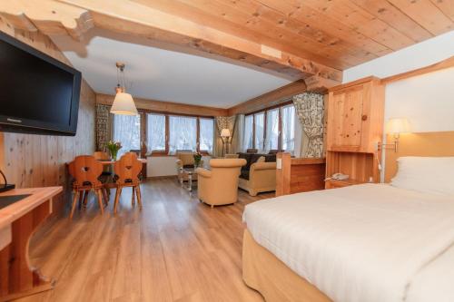 a bedroom with a bed and a dining room at Hotel Steinbock in Klosters