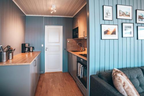 a kitchen with blue walls and a couch in a room at Skårungen - Hotel, Cabins and Camping in Kabelvåg