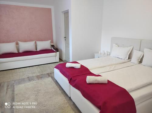 a bedroom with two beds with red and white sheets at Pensiunea Izabel in Lacu Rosu