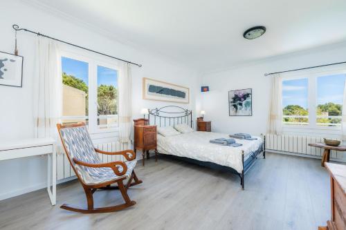 a bedroom with a bed and a chair and windows at Casa Luz in Cala Ratjada
