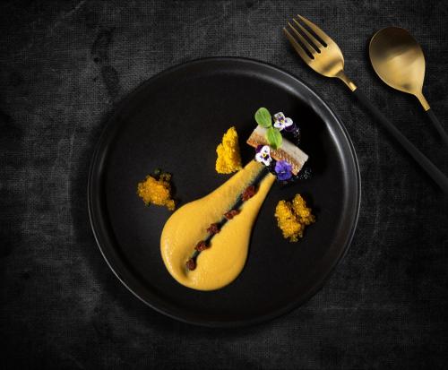 a black plate with a banana dessert on it at Anteliz Suites in Fira