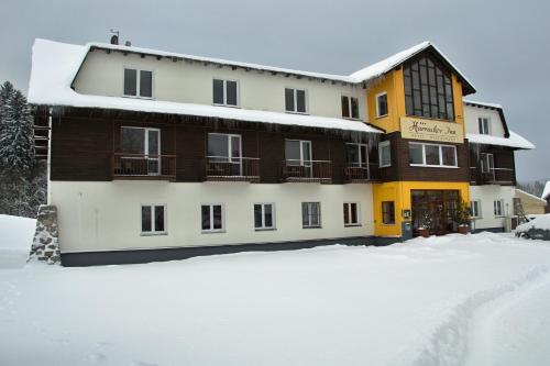 a large building with snow on the ground in front of it at Hotel Harrachov Inn in Harrachov