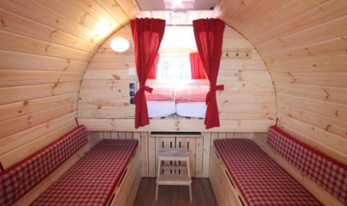ein kleines Zimmer mit roten Bänken und einem Fenster in der Unterkunft Holz-Wohnfass in München-Nymphenburg in München
