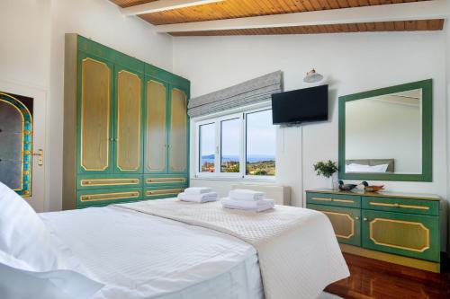 a bedroom with a bed with green cabinets and a window at Villa Elihrisos in Chorafakia