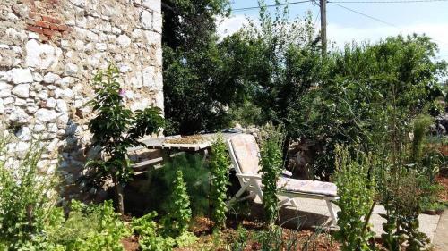 ławka w ogrodzie obok kamiennej ściany w obiekcie Apartments Peter w mieście Dobrinj