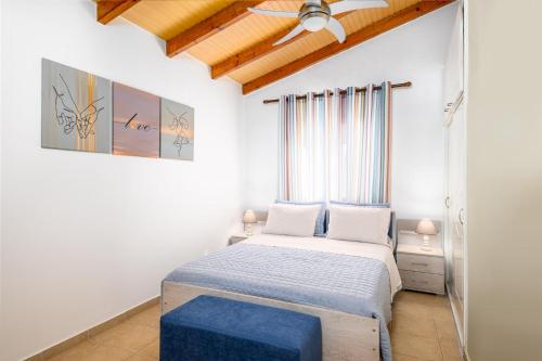 een kleine slaapkamer met een bed en een blauwe kruk bij Akoli Blue - an Elegant residence by the sea in Rodhodháfni