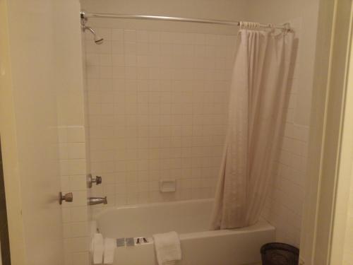 a bathroom with a tub and a shower curtain at Evergreen Inn in Covina