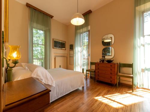 - une chambre avec un lit, une commode et des fenêtres dans l'établissement Villa Cipressi by Victoria Palace, à Pesaro