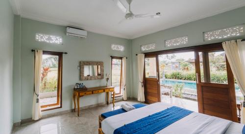 a bedroom with a bed and a desk and windows at Ubud Shanti Rice Field House By Supala in Ubud