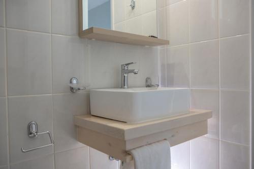 a white bathroom with a sink and a mirror at Captain Nick Aparthotel in Mikros Gialos
