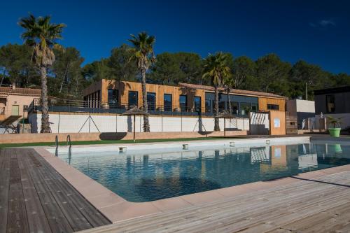 a swimming pool in front of a building with palm trees at Domaine des voiles de Pierrefeu in Pierrefeu-du-Var