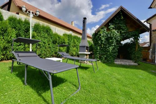 three picnic tables in the grass in a yard at Penzion Kameňák in Horní Planá