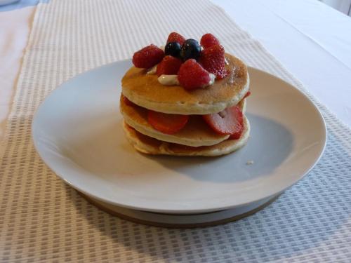 uma pilha de panquecas com morangos e bagas num prato em Tanleys B&B em Grantown on Spey