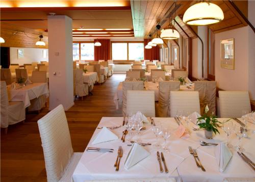 a dining room with white tables and white chairs at Silverpeak in Wengen