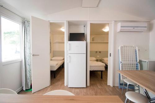 ドゥナ・ヴェルデにあるMobile Home Suiteの白い冷蔵庫とテーブルが備わる客室です。