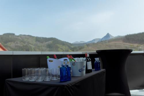 a table with glasses and bottles on a balcony at HOTEL ORDIZIA in Villafranca de Ordizia