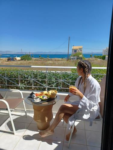 a woman sitting on a chair with a plate of food at Koukounari Apartments in Skala