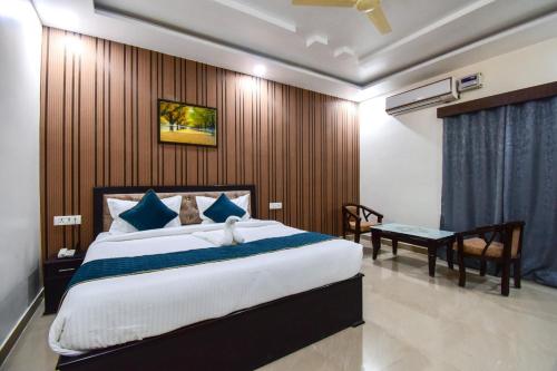 a bedroom with a large bed and a table and a chair at Advantage Inn in Allahābād