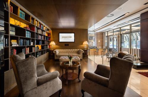 a library with chairs and bookshelves and a tv at Pepperclub Hotel in Cape Town