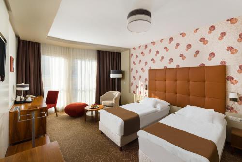 a hotel room with two beds and a couch at Corso Hotel Pécs in Pécs