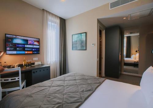 a hotel room with a bed and a desk and a television at TbiliSee Hotel in Tbilisi City