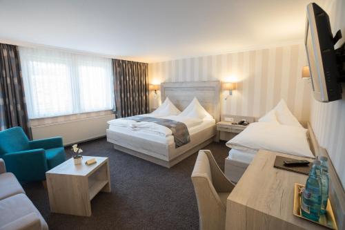 a hotel room with two beds and a couch at Hotel Garni Fürst von Waldeck in Willingen