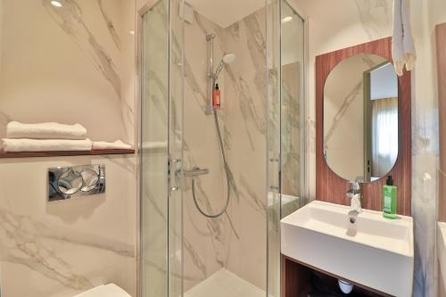 a bathroom with a shower and a sink and a mirror at Hotel du Pin Nice Port in Nice