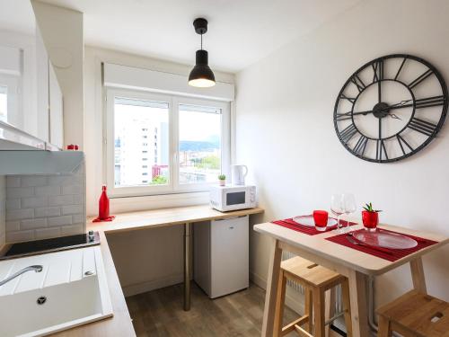 a kitchen with a table and a clock on the wall at 1er Mai in Clermont-Ferrand