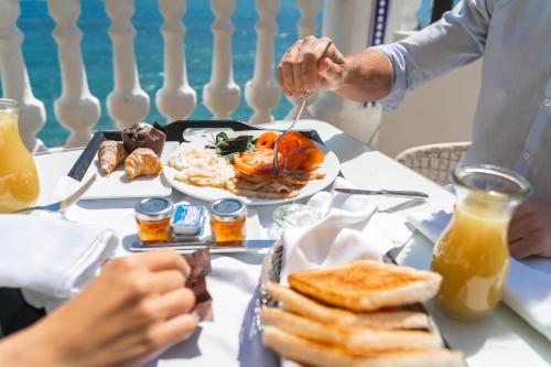 Hotel Boutique Villa Venecia في بنيدورم: رجل يأكل الطعام على طاولة مع طبق من الطعام