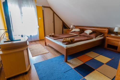 Schlafzimmer mit einem Bett mit einem Teppich und einem Fenster in der Unterkunft Gál Apartmanház in Harkány